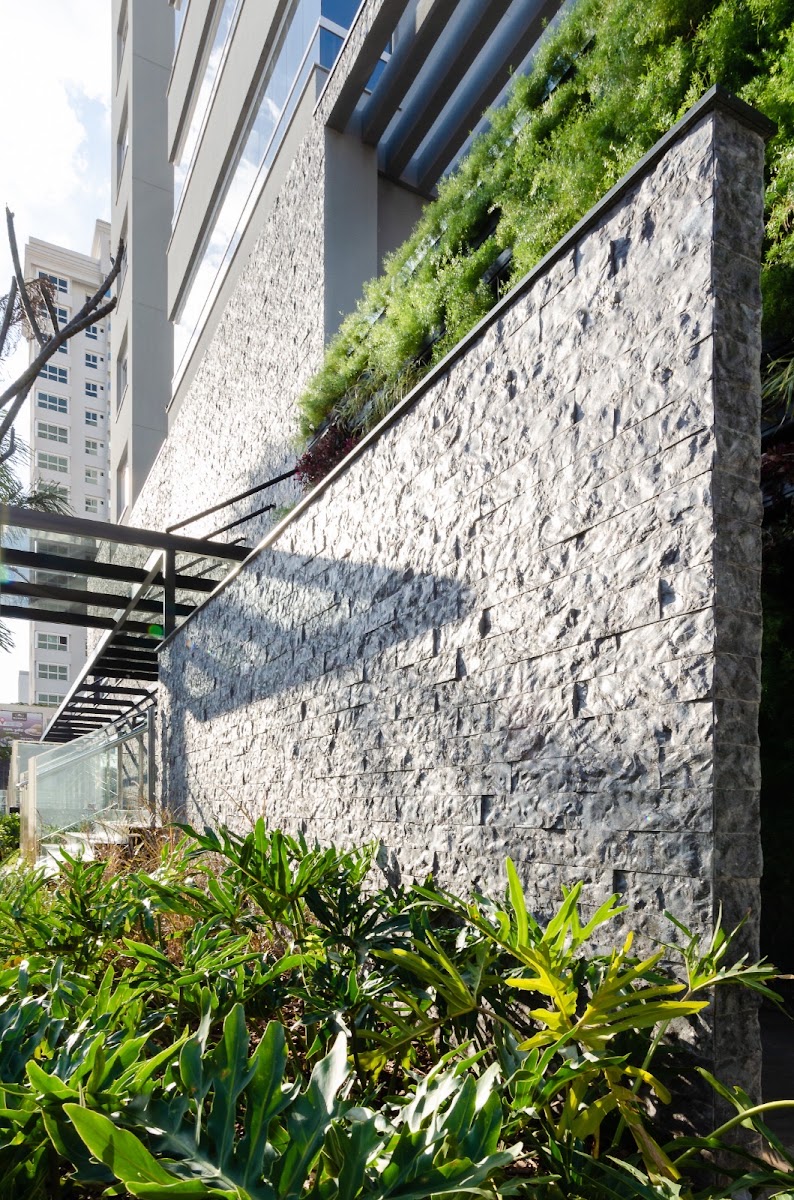 Jardim lateral com muro revestido em pedra Matrix
