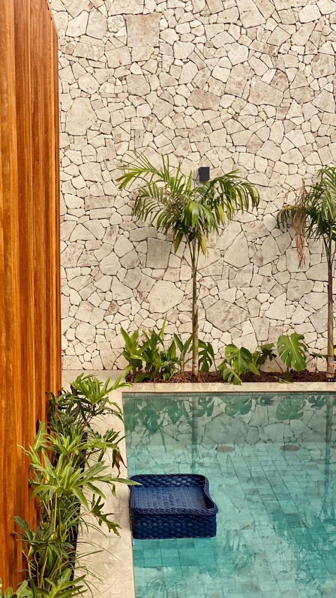Área de piscina com parede em pedra natural clara